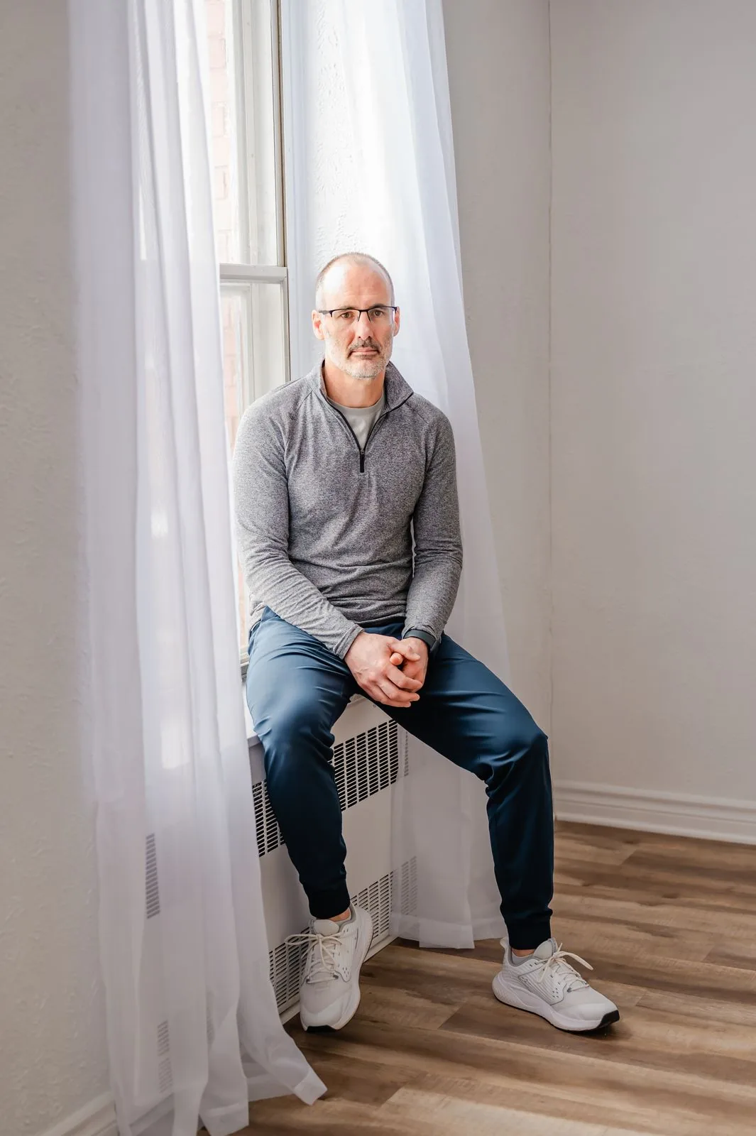Marcel West seated on a plyo box beside a bright window in the quiet studio