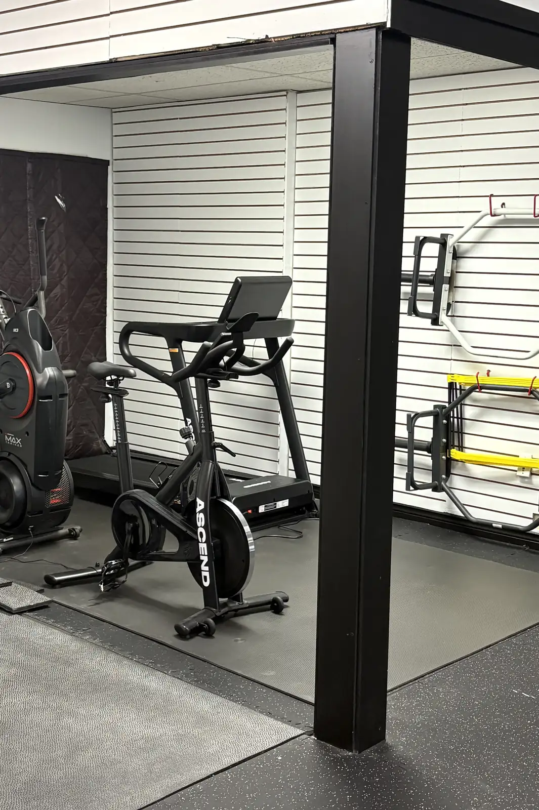 The cardio corner at MW Fitness and Coaching, with a spin bike, treadmill and air bike beside the rig
