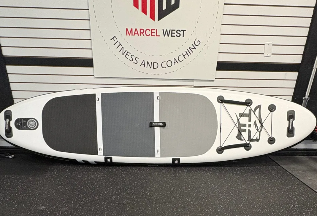 An inflatable paddle board with paddle and gear laid out at the MW Rentals studio